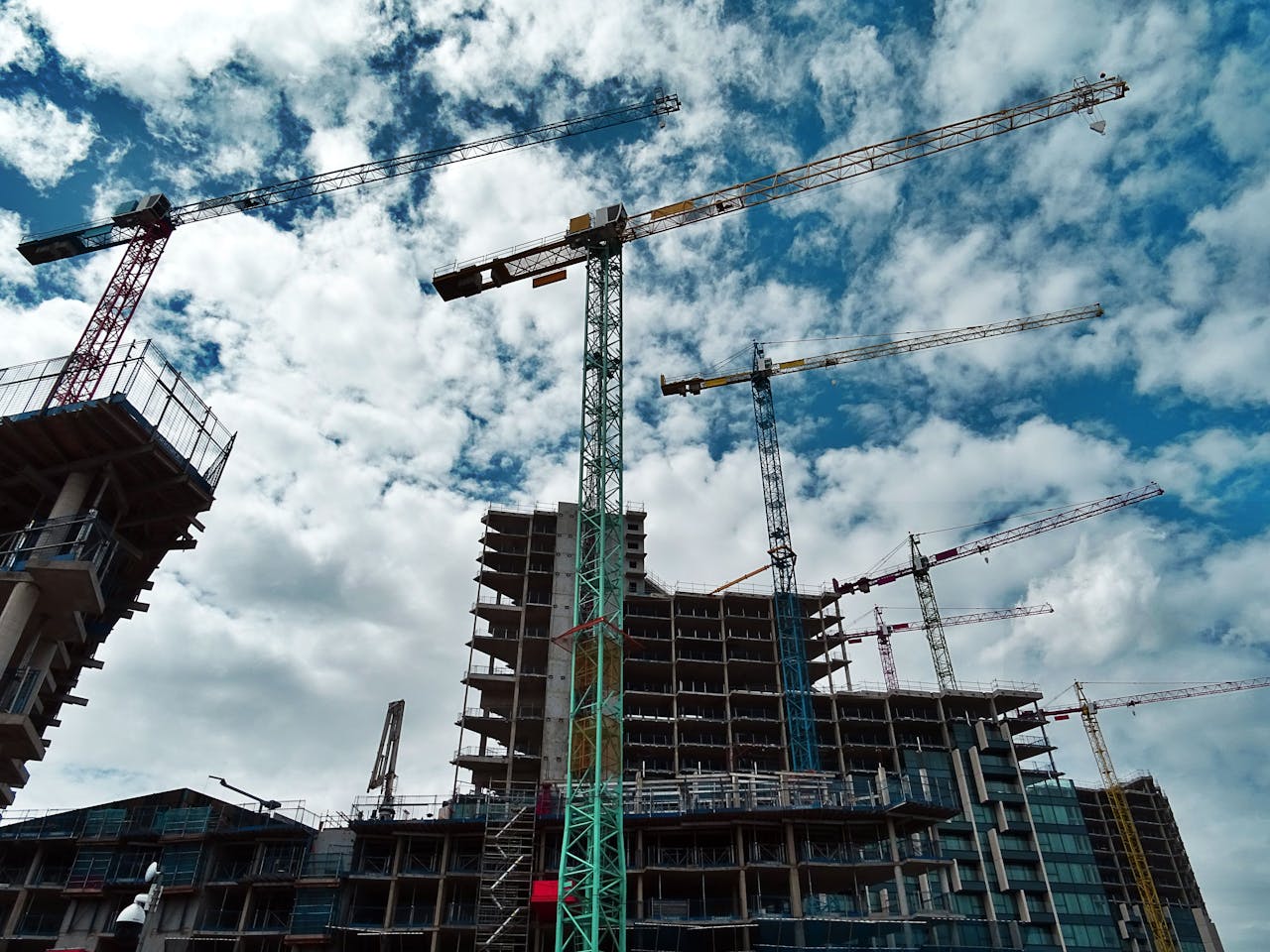 Home Urban construction site with numerous cranes framing rising skyscrapers against a blue sky.